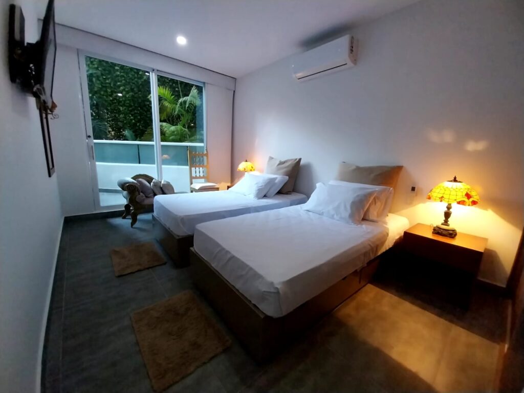 Habitación moderna con dos camas, decoración luminosa y balcón con vista tropical en Edificio Spiaggia Di Cartagena Apartamento 201