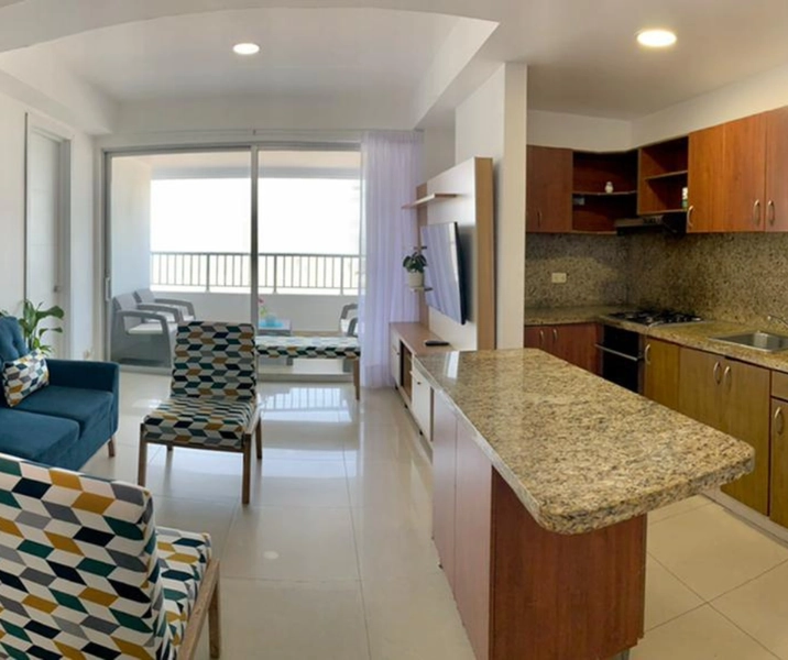 Vista de la cocina, sala y comedor, al fondo el balcón con vista al mar del apartamento vacacional 604 Edificio Renta vacacional en Cartagena, Edificio Palmetto Cartagena